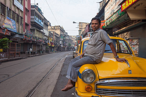 Taxi driver sitting on a yellow Ambassador in Kolkata, India stock photo