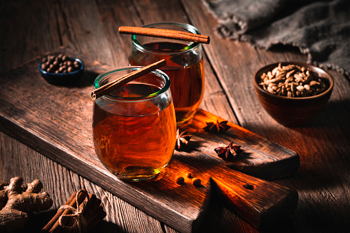 Tea or Chai tea on wooden board with spices as a cozy hot drink