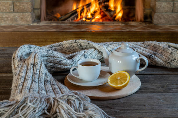 Tea with lemon in front of burning fireplace in a country house. stock photo