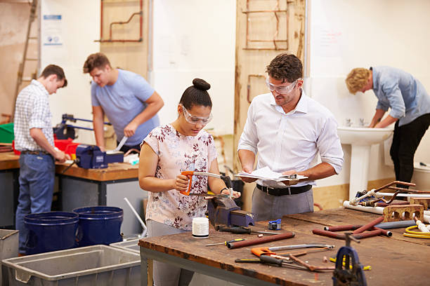 Teacher Helping College Students Studying Plumbing Teacher Helping College Students Studying Plumbing Wearing Protective Goggles african american plumber stock pictures, royalty-free photos & images