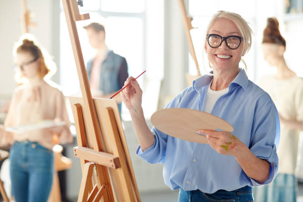 Teacher of painting Senior student or teacher of school of arts looking at camera while painting with oil colors individual event stock pictures, royalty-free photos & images