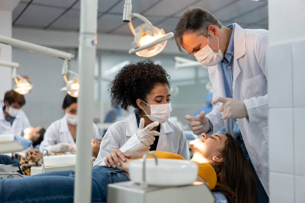 teacher supervising a student examining a patient at dental school - aluno dentista imagens e fotografias de stock