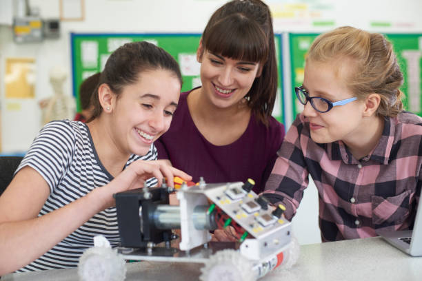 Teacher Talking To Female Pupils Studying Robotics In Science Lesson Teacher Talking To Female Pupils Studying Robotics In Science Lesson middle school teacher stock pictures, royalty-free photos & images