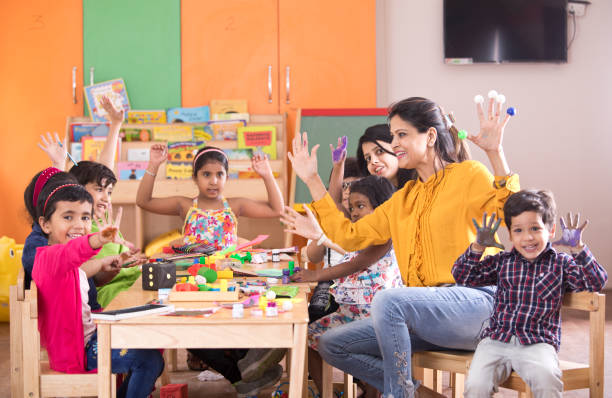 Teacher with preschoolers finger painting at class Teacher with preschool students having fun while finger painting at class kids playing with toys stock pictures, royalty-free photos & images