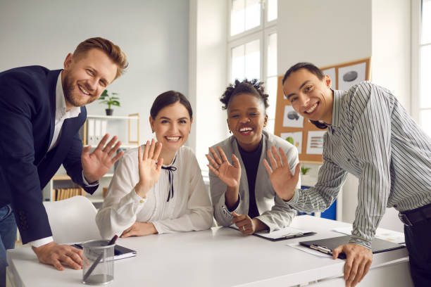 Team of business people waving hello at camera greeting international coworkers in online meeting stock photo