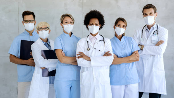 Team of confident medical experts with protective face masks. Group of healthcare workers wearing protective face masks while standing with arms crossed and looking at camera. sports team stock pictures, royalty-free photos & images