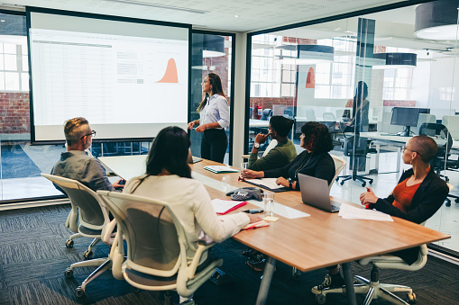 Team of creative businesspeople having a presentation in a boardroom. Group of modern businesspeople attending a financial briefing in a modern workplace. Businesspeople analysing statistical details.