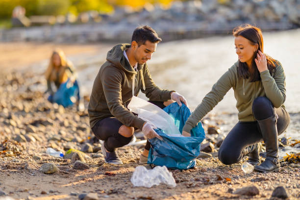 Team of dedicated and smiling volunteers collecting plastic garbage at beach stock photo