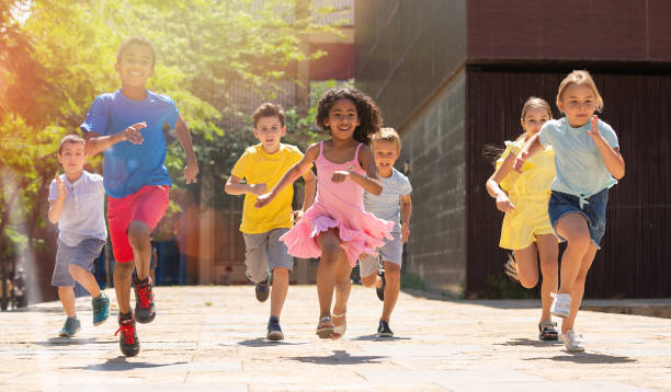 Team of positive kids running in race in the street and laughing stock photo