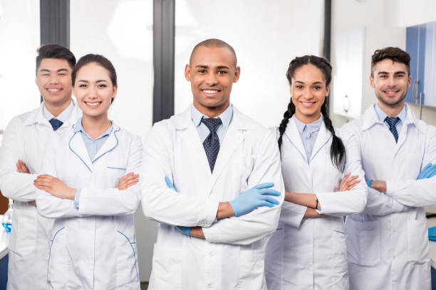 Team of professional doctors Team of young professional doctors standing together in laboratory, posing with arms crossed lab coat stock pictures, royalty-free photos & images