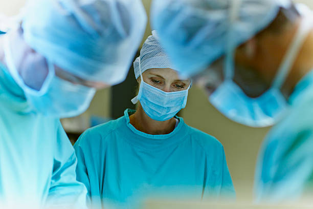 team of surgeons in operation room - chirurg stock-fotos und bilder