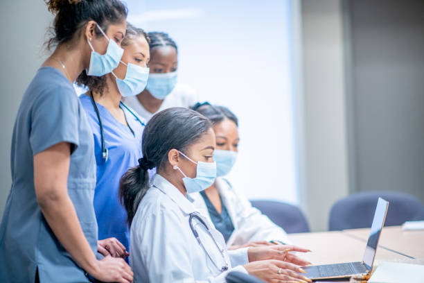Team of woman medical professionals working together A diverse group of women wearing medical clothing discuss and cooperate with each other in an educational/medical setting. medical student stock pictures, royalty-free photos & images