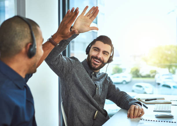 Teamwork is the answer to it all Shot of two call centre agents high fiving each other while working in an office sales occupation stock pictures, royalty-free photos & images