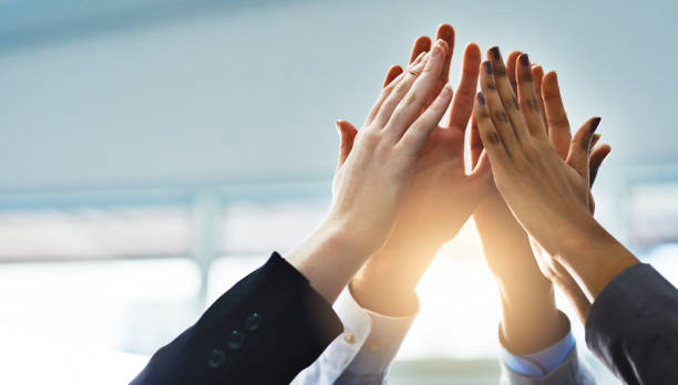 Teamwork! Low angle shot of a group of businesspeople high fiving while standing in their office high five stock pictures, royalty-free photos & images
