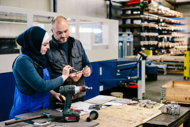 teamwork: technician explains a work tool to a young woman in a workshop stock photo