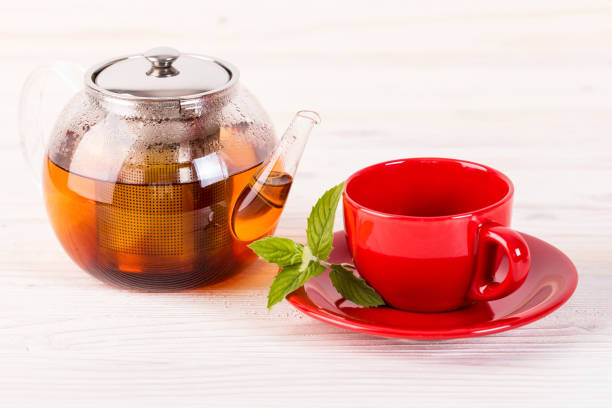 Teapot and red cup on wooden table stock photo