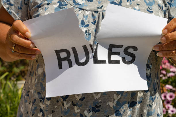 Tearing up a RULES sign A female tearing up a printed sign that says RULES. rule breaker stock pictures, royalty-free photos & images