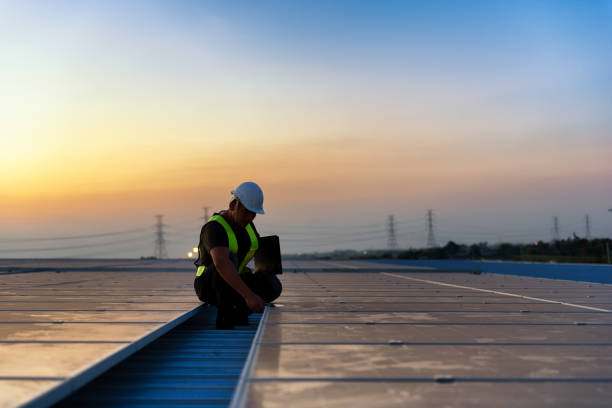 Technician checking Photovoltaic cells panels on factory roof, Maintenance of the solar panels, Engineer service, Inspecor concept. Silhouette Photo. stock photo