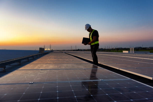 Technician checking Photovoltaic cells panels on factory roof, Maintenance of the solar panels, Engineer service, Inspecor concept. Silhouette Photo. stock photo