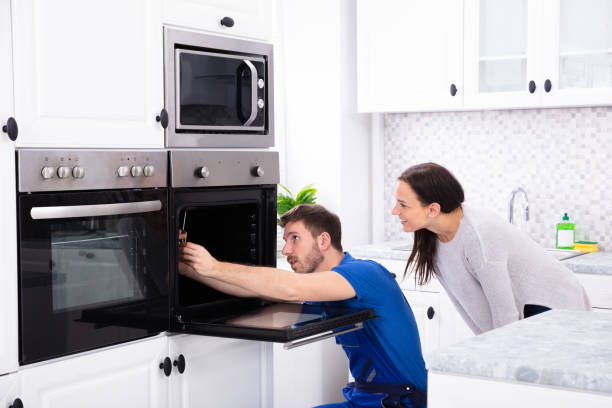 Technician In Overall Fixing Oven In Kitchen Smiling Young Woman Looking At Technician Fixing Oven In Kitchen appliance stock pictures, royalty-free photos & images