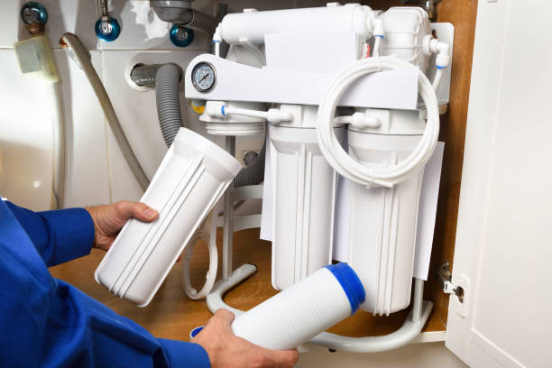 Technician installing reverse osmosis equipment under the sink detail stock photo