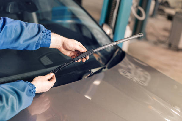 Technician is changing windscreen wipers on a car station. stock photo