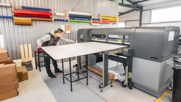 Technician operator works on large premium industrial printer plotter machine Technician worker operator works on large premium industrial printer and plotter machine in digital printshop office printing press stock pictures, royalty-free photos & images