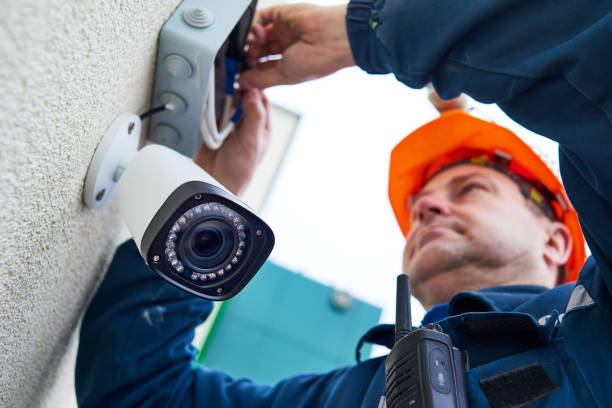 Technician worker installing video surveillance camera on wall stock photo