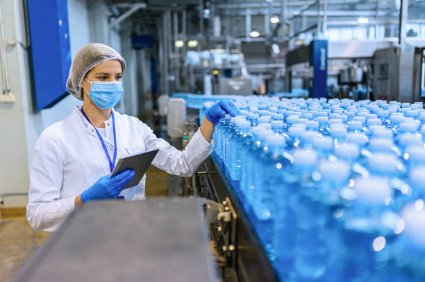 Technologist in bottling factory checking water bottles before shipment. stock photo