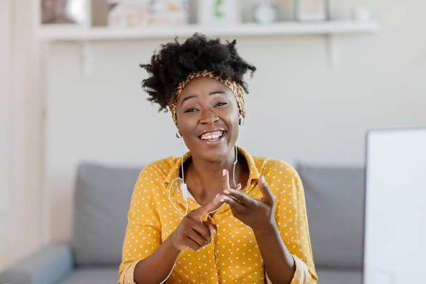 Technology makes connecting with the outside world so much easier Pretty African American Woman Looking at Camera and Taking Part Video call Involved in Virtual Conferencing With Colleagues During Video Conference in the Office looking at camera stock pictures, royalty-free photos & images