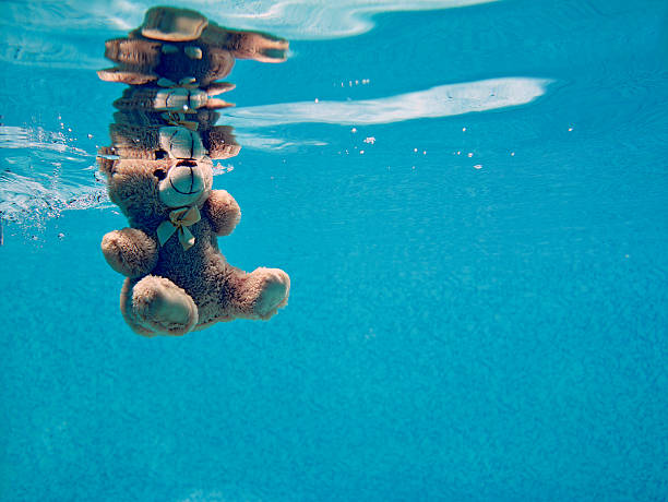 teddy bear drowning underwater stock photo
