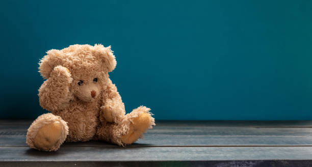 тедди медведь грустно, сидя на деревянном полу, синий пустой фон комнаты, копировать пространство - blue monday стоковые фото и изображения