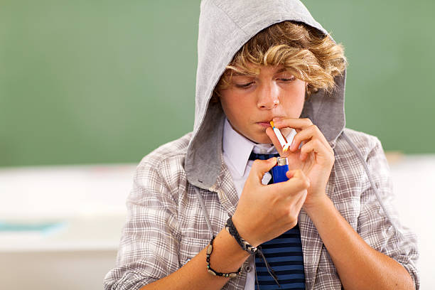 teen boy lighting cigarette stock photo