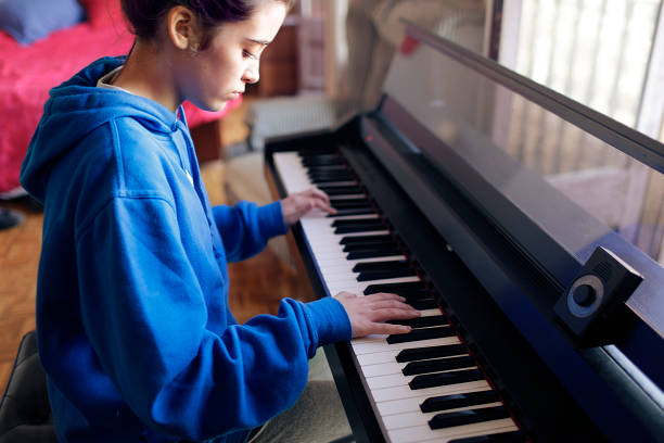 teen girl playing the piano stock photo