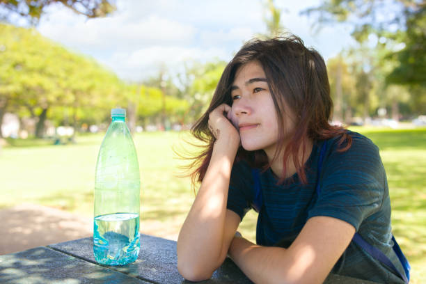 Teen girl resting chin on hand outdoors at picnic table stock photo