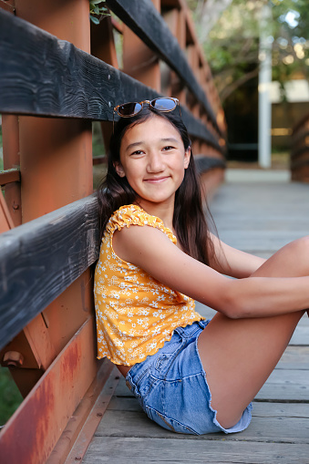 Teen girl sitting on bridge smiling at camera