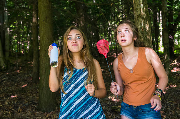teen girls make faces chasing insects in a forest - vliegenmepper stockfoto's en -beelden
