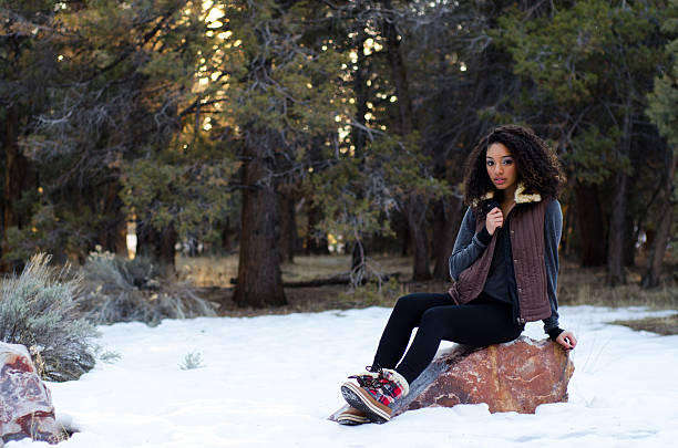 Teen in winter wardrobe posing on a rock stock photo
