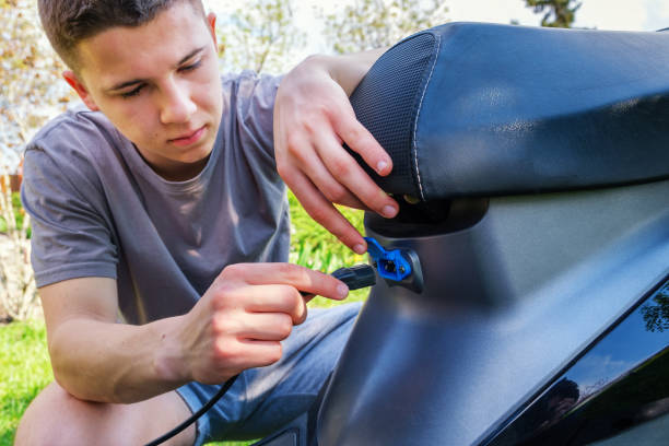 tiener voegt stekker in het opladen stopcontact van elektrische scooter. - alleen één tienerjongen stockfoto's en -beelden
