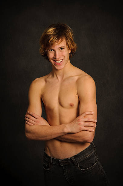 Teen Male Smiling and Shirtless Teen Male Smiling and Shirtless With Arms Folded teenage boys men blond hair muscular build stock pictures, royalty-free photos & images