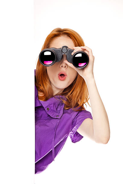 Teen redhead girl with binoculars isolated on white background stock photo