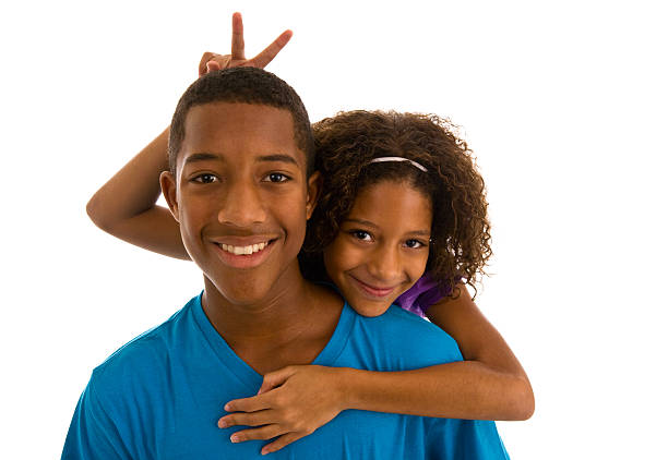 Teenage boy and sister embracing and gesturing bunny ears stock photo