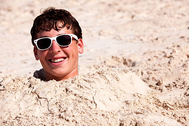 Teenage Boy Buried in Sand  buried stock pictures, royalty-free photos & images