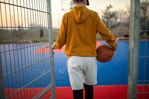 tiener die openlucht basketbalhof ingaat - basketball player back stockfoto's en -beelden