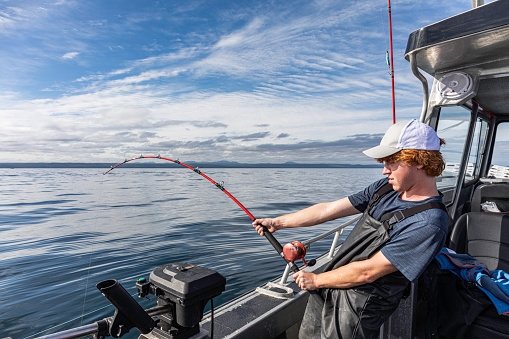 A Teenage boy concentrating on reeling in a large Chinook salmon (King salmon) that he is fighting. He is fishing at the north end of Graham Island, Haida Gwaii (Queen Charlotte Islands), British Columbia, Canada.