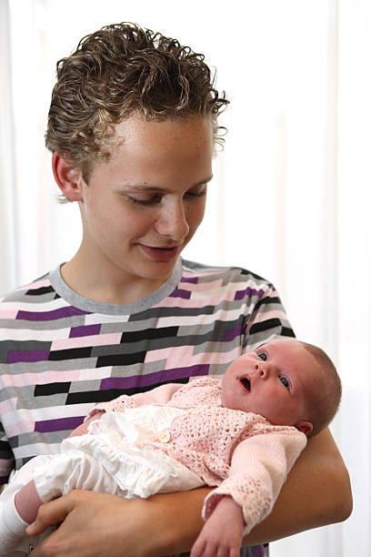 Teenage Boy Holding Newborn Baby Girl stock photo