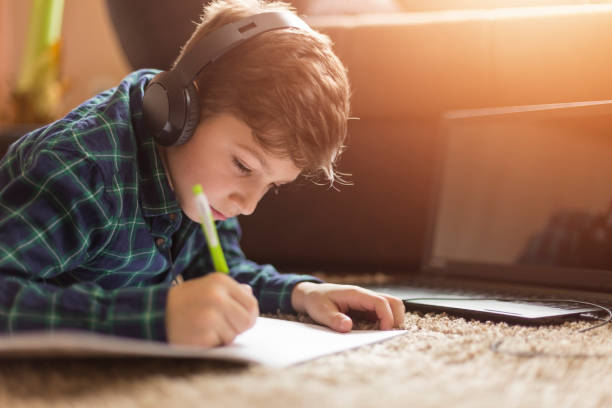teenage boy luisteren naar muziek terwijl het doen van huiswerk - alleen één tienerjongen stockfoto's en -beelden