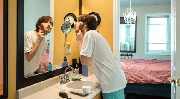 Teenage boy personal hygiene Teenage boy personal hygiene: he is combing facial his hair in front of bathroom mirror. mutton chops stock pictures, royalty-free photos & images