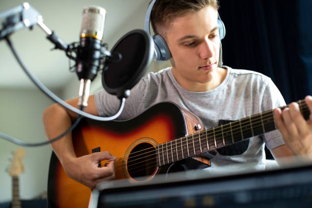 tiener die gitaar speelt en muziek thuis opneemt - muziekanten stockfoto's en -beelden