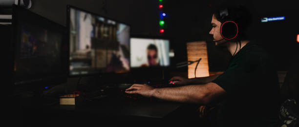 Teenage Boy Playing Multiplayer Games on Desktop Pc in his Dark Room stock photo